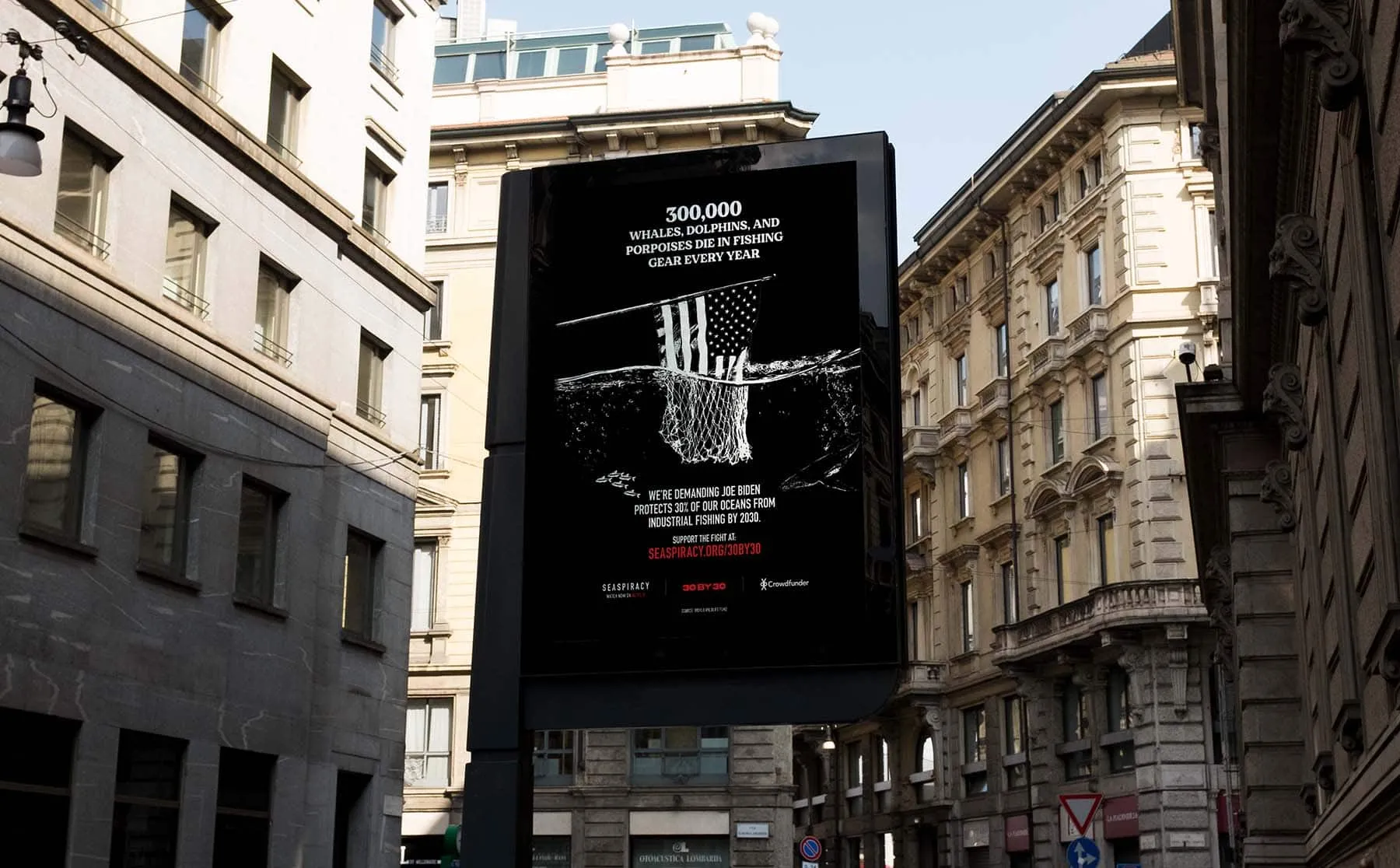 An illuminated city billboard reading '300,000 whales, dolphins and porpoises die in fishing gear every year', demanding action from Joe Biden