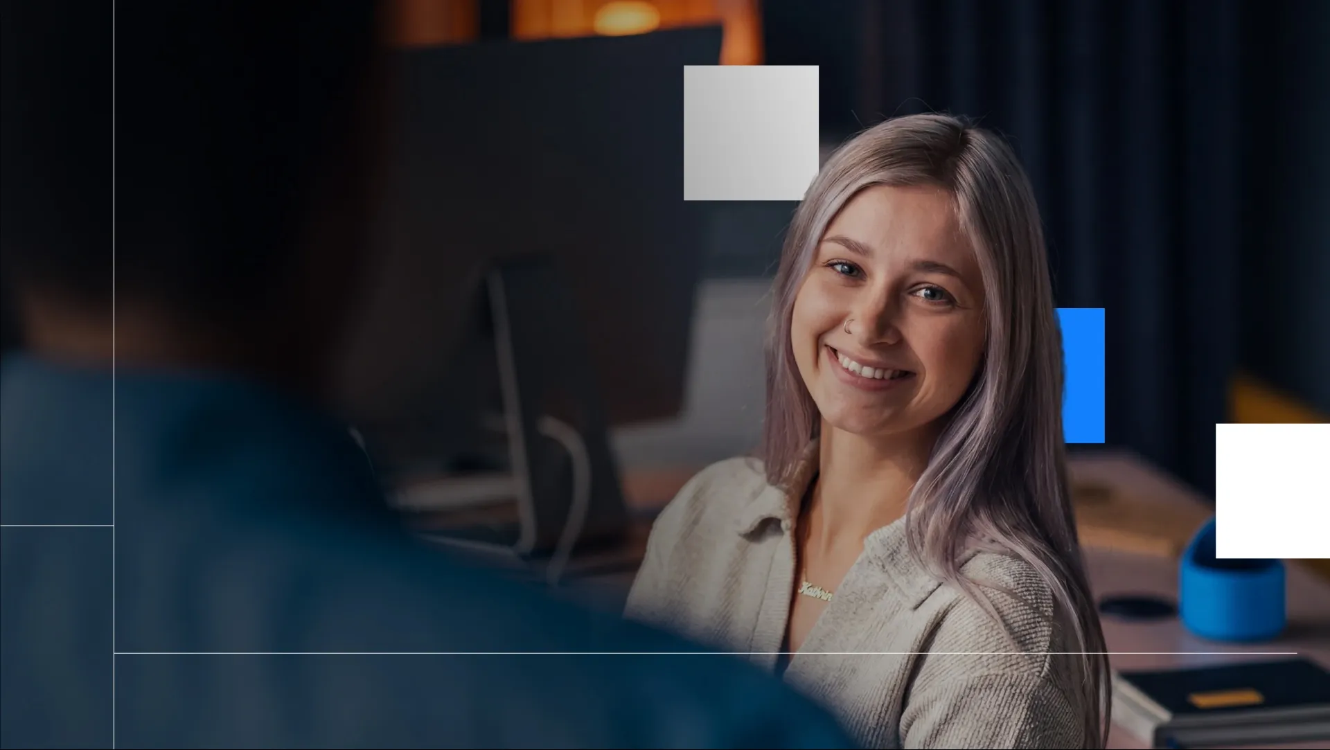 Appcast team member smiling at a desk in a low-lit office