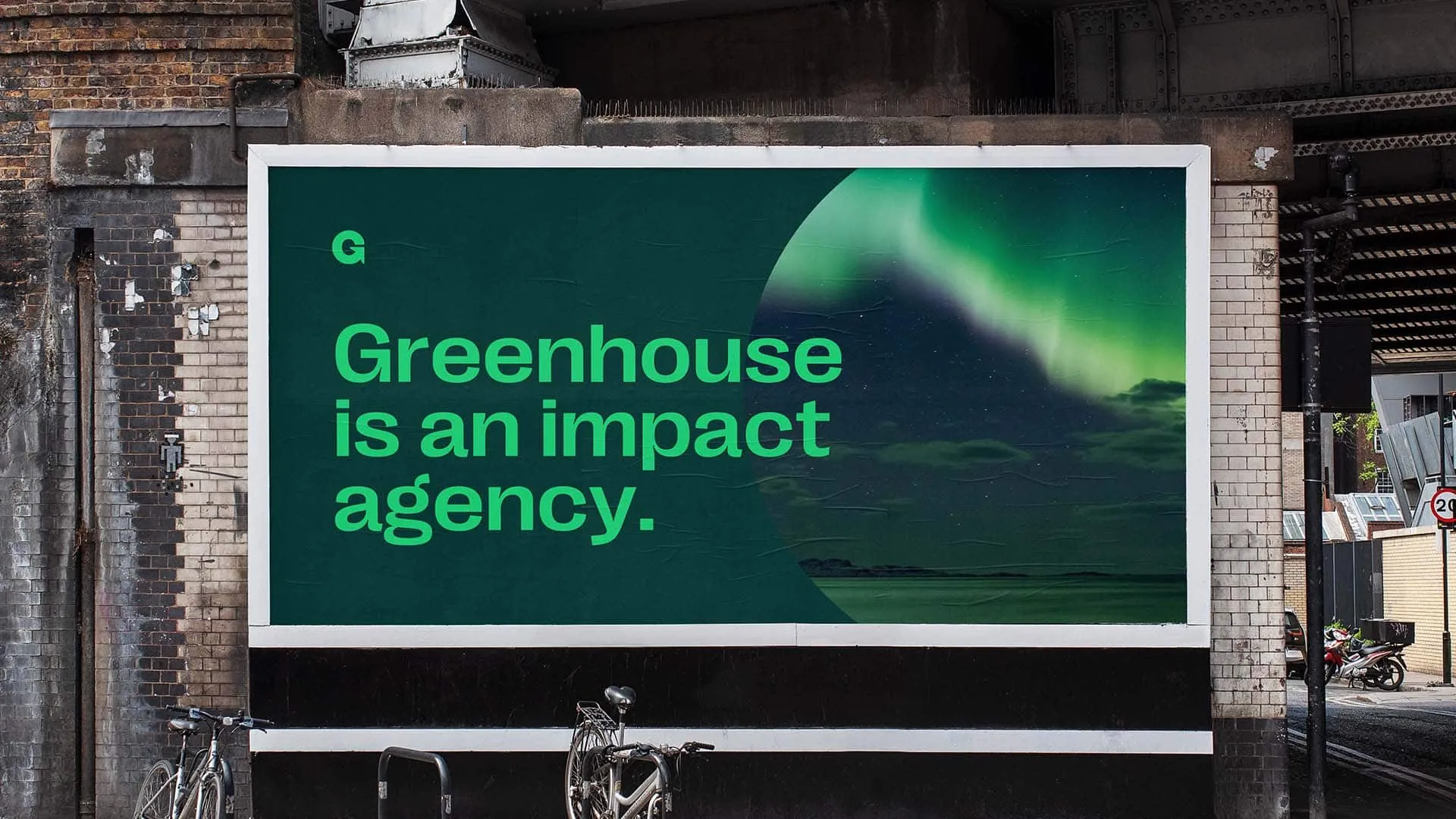 Greenhouse billboard reading "Greenhouse is an impact agency" against a night-sky aurora backdrop