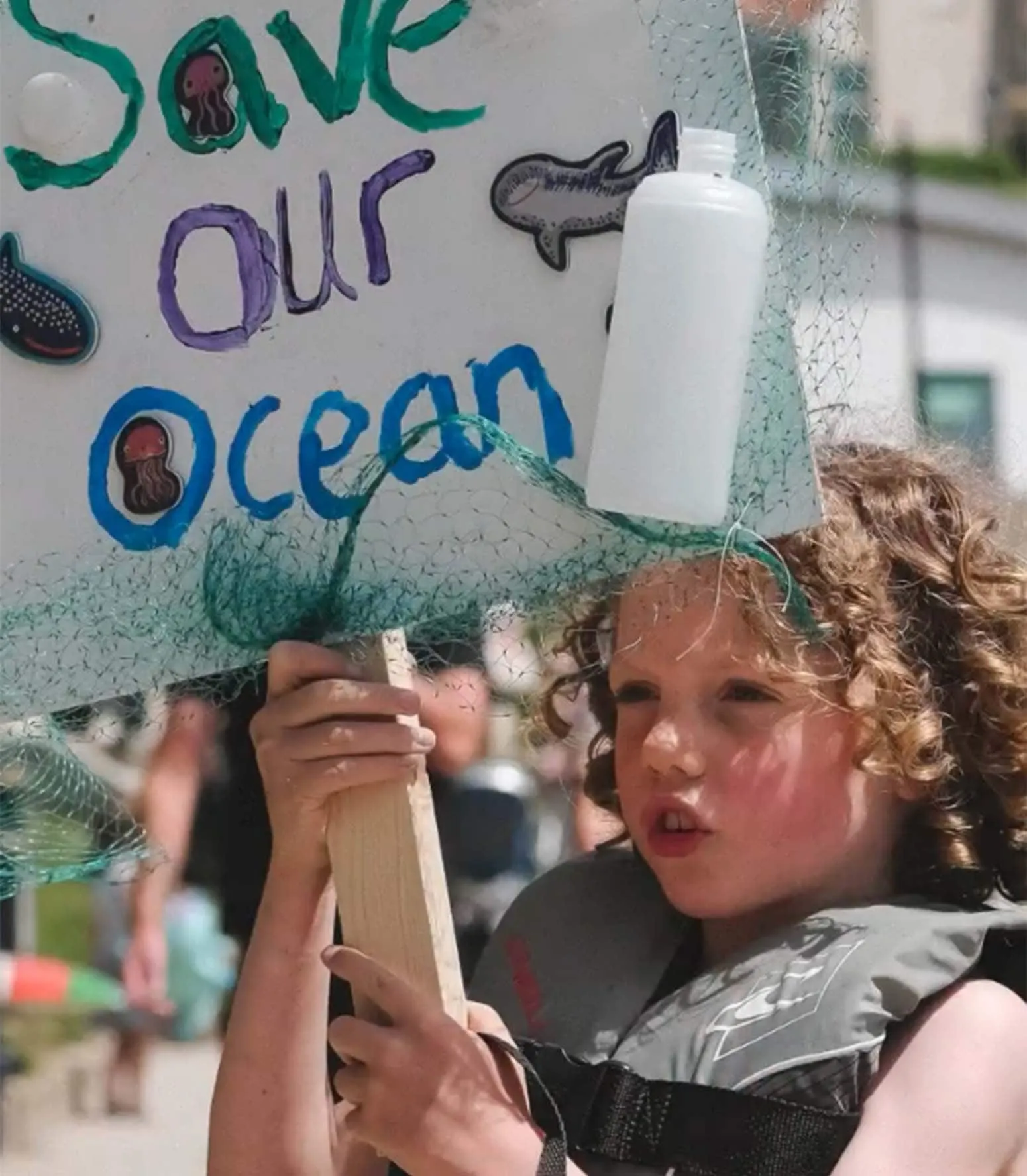 A young activist holding a hand-painted 'Save our Ocean' protest sign